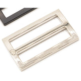 Nickel-plated rectangular metal slider hardware with wide mouth opening, shown alongside black hardware pieces on white background.