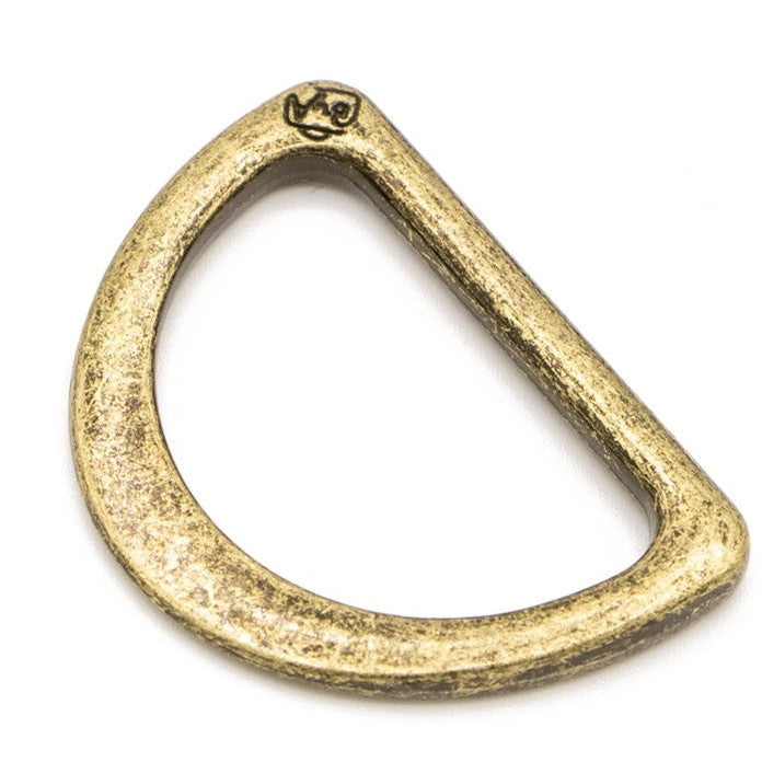 Antique brass D-ring hardware with weathered golden finish and small logo marking at the top.