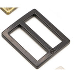 Black metal rectangular slider buckles with wide openings and smooth edges, showing two overlapping hardware pieces.