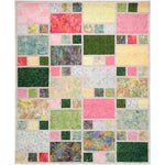 A colorful patchwork quilt featuring rectangular fabric blocks in pink, green, yellow, and blue arranged in an asymmetrical city window pattern.