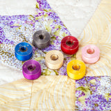 colorful class 15 prewound bobbins on a quilt