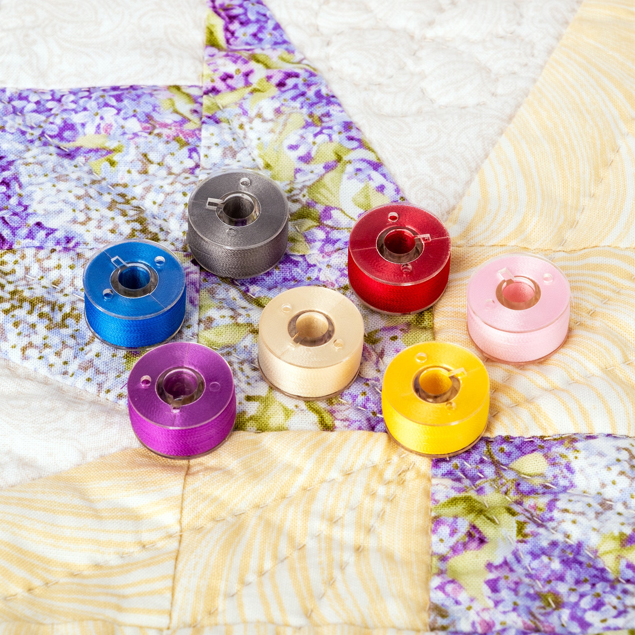 colorful class 15 prewound bobbins on a quilt