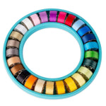 Colorful prewound bobbins in circular turquoise organizer, rainbow spectrum from white to yellow to blue to pink.
