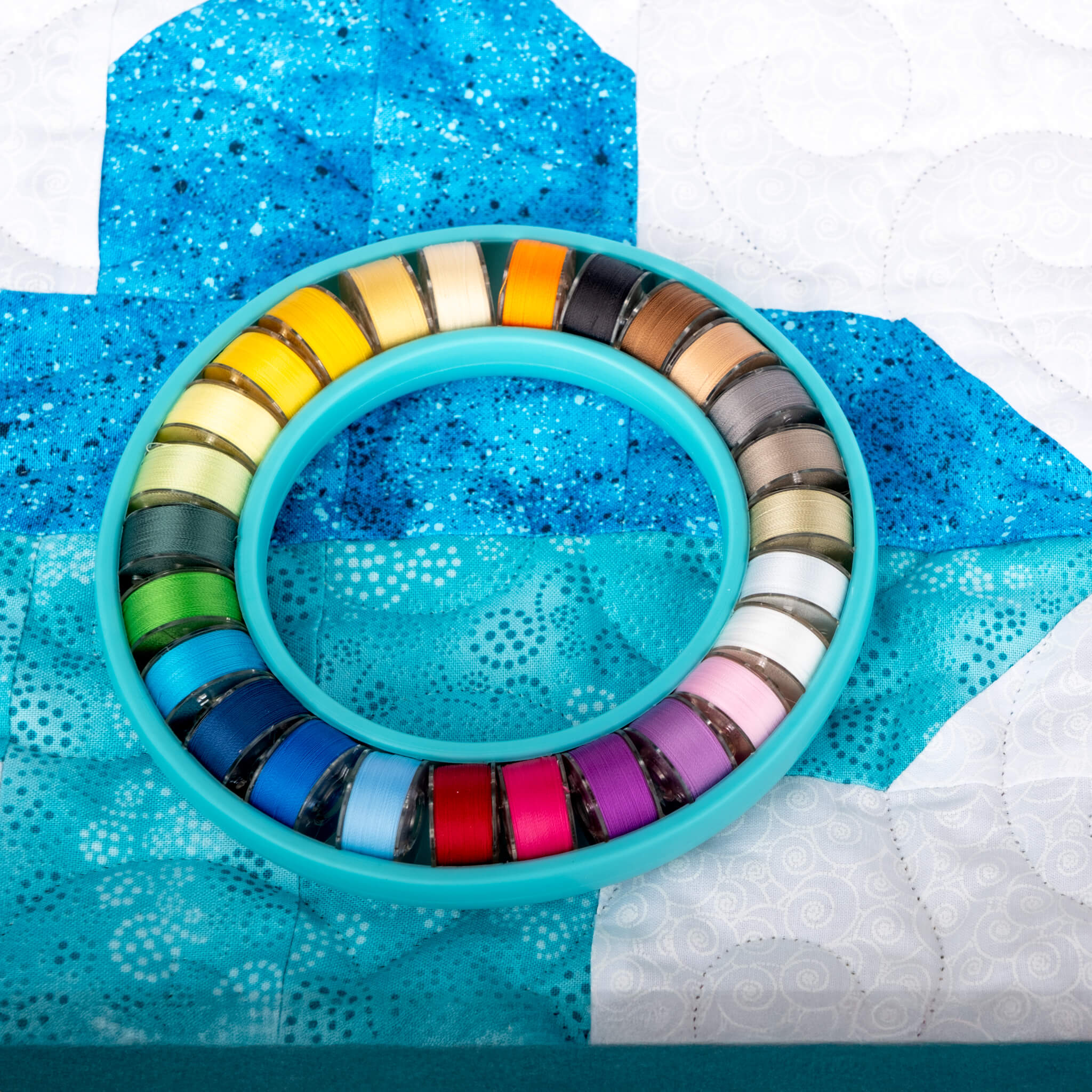 color wheel prewound bobbin set on top of a blue and white quilt