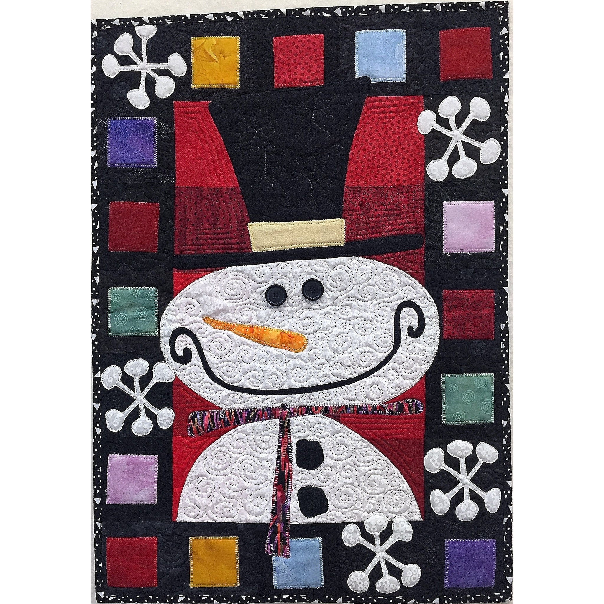 A festive quilted wall hanging featuring a smiling snowman with red hat and scarf, surrounded by colorful fabric squares and white snowflakes on a black background.