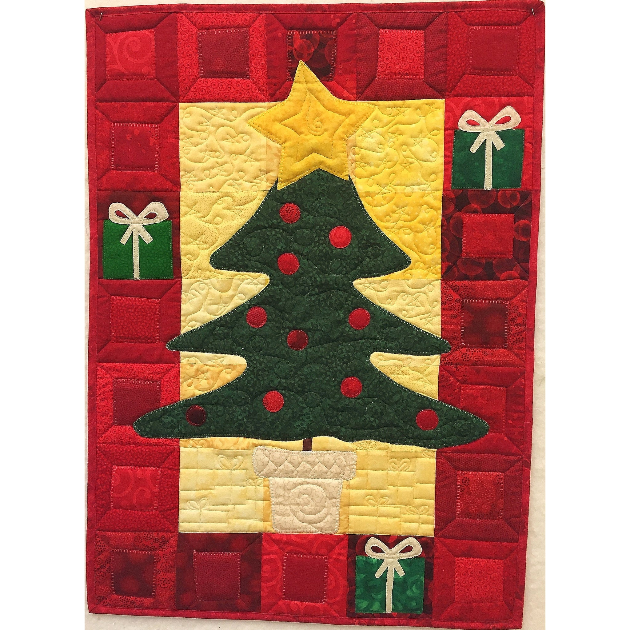 A festive Christmas quilt featuring a green tree with red ornaments on a yellow star background, surrounded by red patchwork squares and small green gift box appliques.