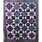 Patchwork quilt with diamond and square patterns in purple, teal, and cream batik fabrics with coordinating border.