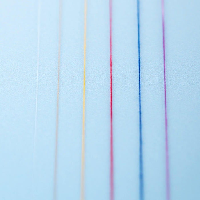 macro photo showing the thickness of different threads against a light blue background