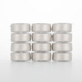 Twelve clear plastic bobbins of light gray thread arranged in a 4x3 grid, each filled with fine polyester thread