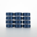 Twelve spools of navy blue thread arranged in four rows of three, each on clear plastic bobbins