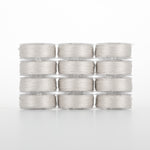 Twelve clear plastic bobbins of light gray thread arranged in a 4x3 grid, showing wound thread through transparent cases