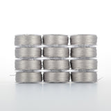 Twelve clear plastic bobbins of gray thread arranged in a 4x3 grid, each bobbin filled with fine gray sewing thread