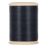 A spool of dark blue yli threads hand quilting thread on a 500 yd spool