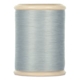 Gray hand quilting thread wound on cream plastic spool with smooth, even finish