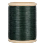 Green hand quilting thread wound on wooden spool with cream-colored ends