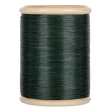 Green hand quilting thread wound on wooden spool with cream-colored ends