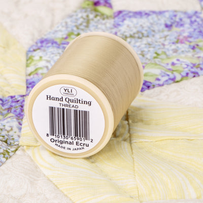 spool of original ecru hand quilting thread on a quit