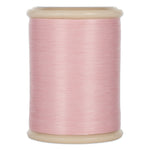 Pink hand quilting thread wound on cream plastic spool with visible thread texture