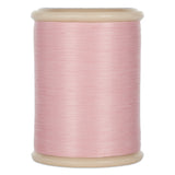 Pink hand quilting thread wound on cream plastic spool with visible thread texture