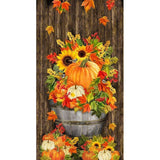 Autumn-themed fabric panel featuring orange pumpkins, sunflowers, and colorful fall leaves arranged in a wooden barrel against brown wood background.