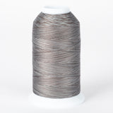 Gray and brown variegated thread cone with white plastic cap, multicolored fossil-toned thread on industrial spool.