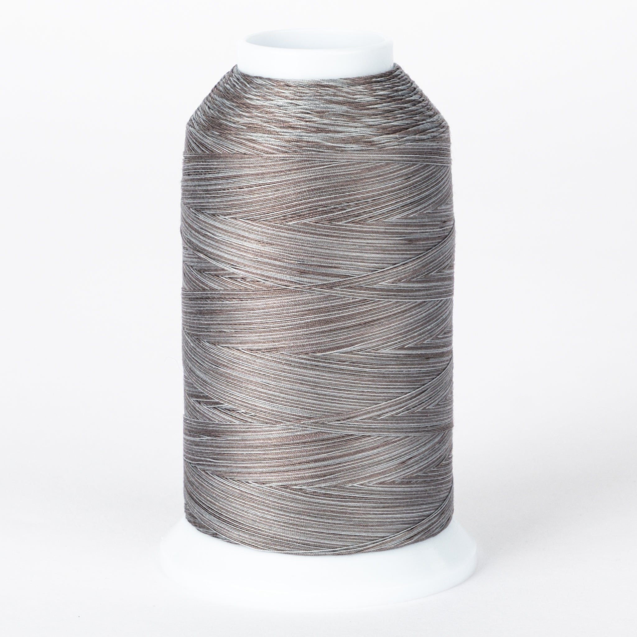 Gray and brown variegated thread cone with white plastic cap, multicolored fossil-toned thread on industrial spool.
