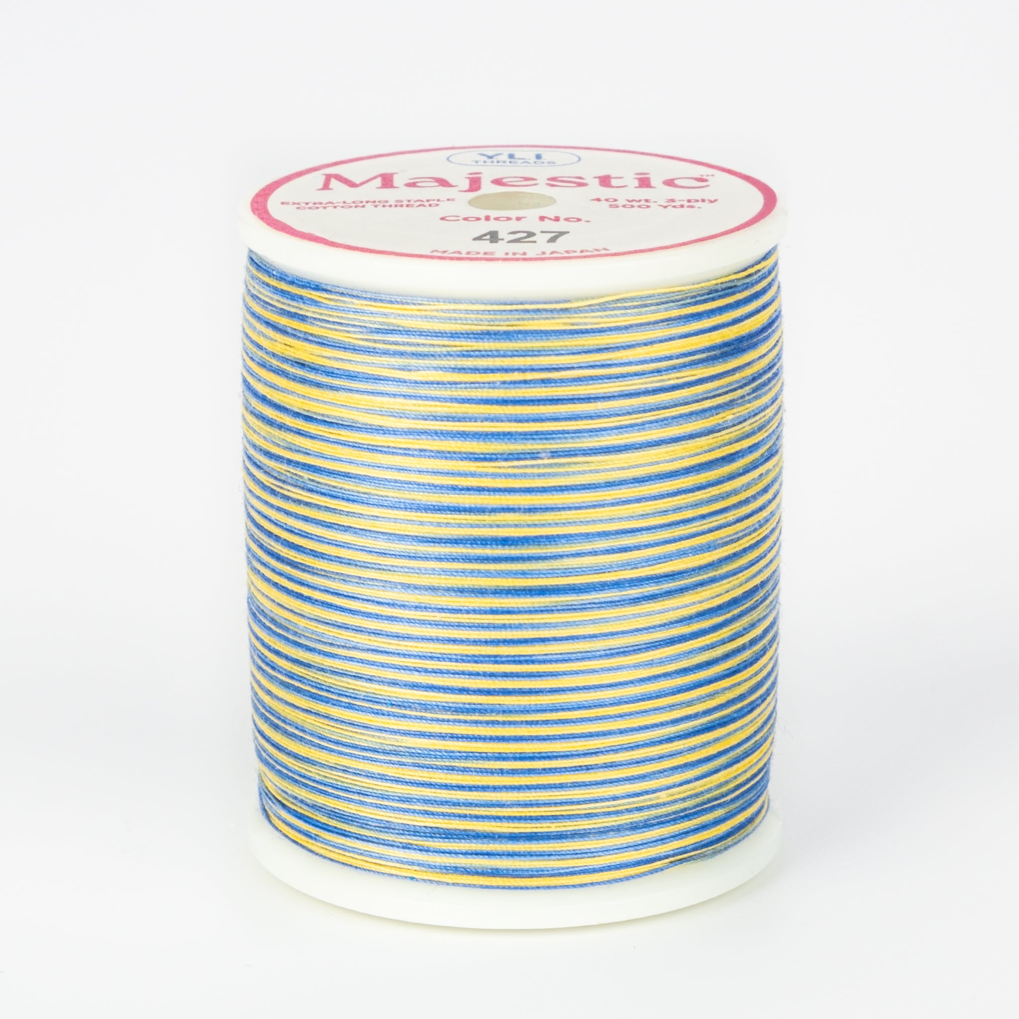 Multicolored blue and yellow variegated thread on white spool with Majestic brand label, color 427 Moonbeam