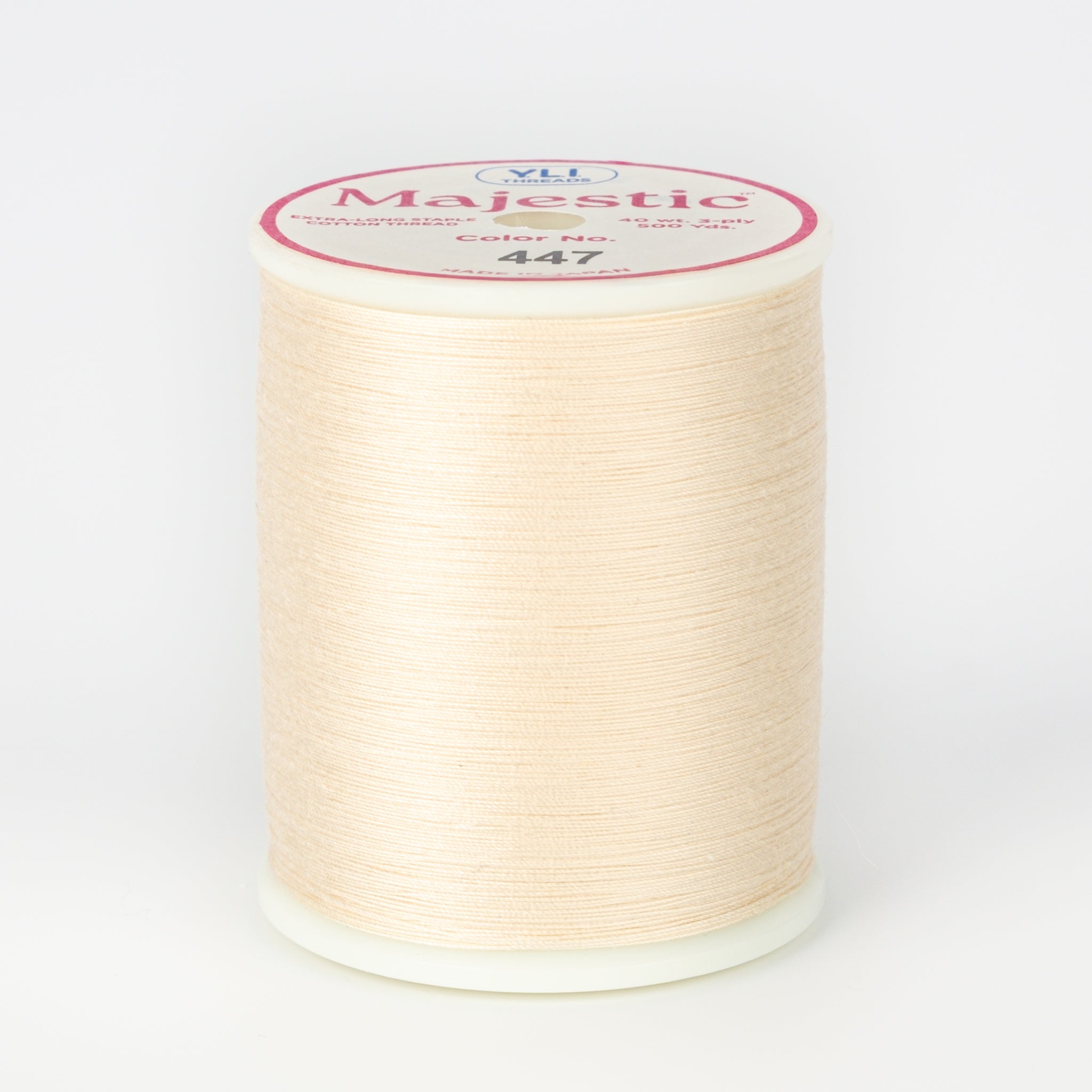Cream colored Majestic 40 wt thread on white plastic spool with pink and white label showing color number 447