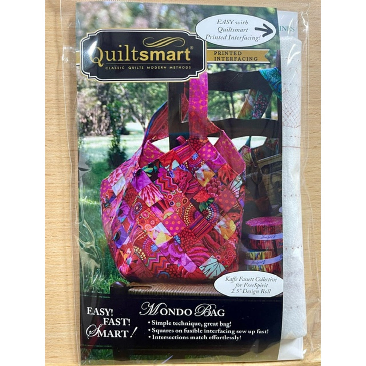 Quiltsmart Mondo Bag sewing pattern package featuring a vibrant patchwork tote bag in pink, red, and purple fabrics with printed interfacing technology.