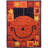 Halloween-themed quilt featuring an orange pumpkin with black face on dark background, surrounded by colorful patchwork border with yellow stars.
