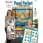 Two women display colorful quilts featuring sun, wolf, and elephant panels with geometric borders in blues, yellows, and earth tones.