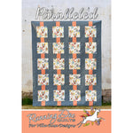 A quilt pattern showing a grid design with floral squares connected by coral-colored sashing strips on a blue-gray background.