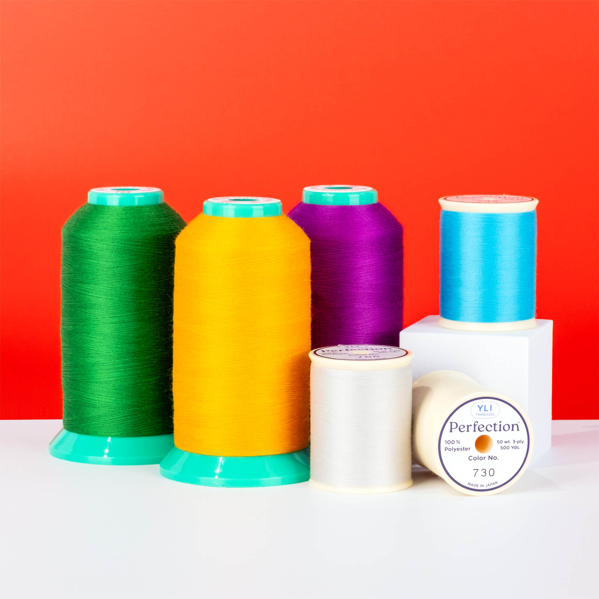 colorful cones and spools of perfection polyester thread on a red background