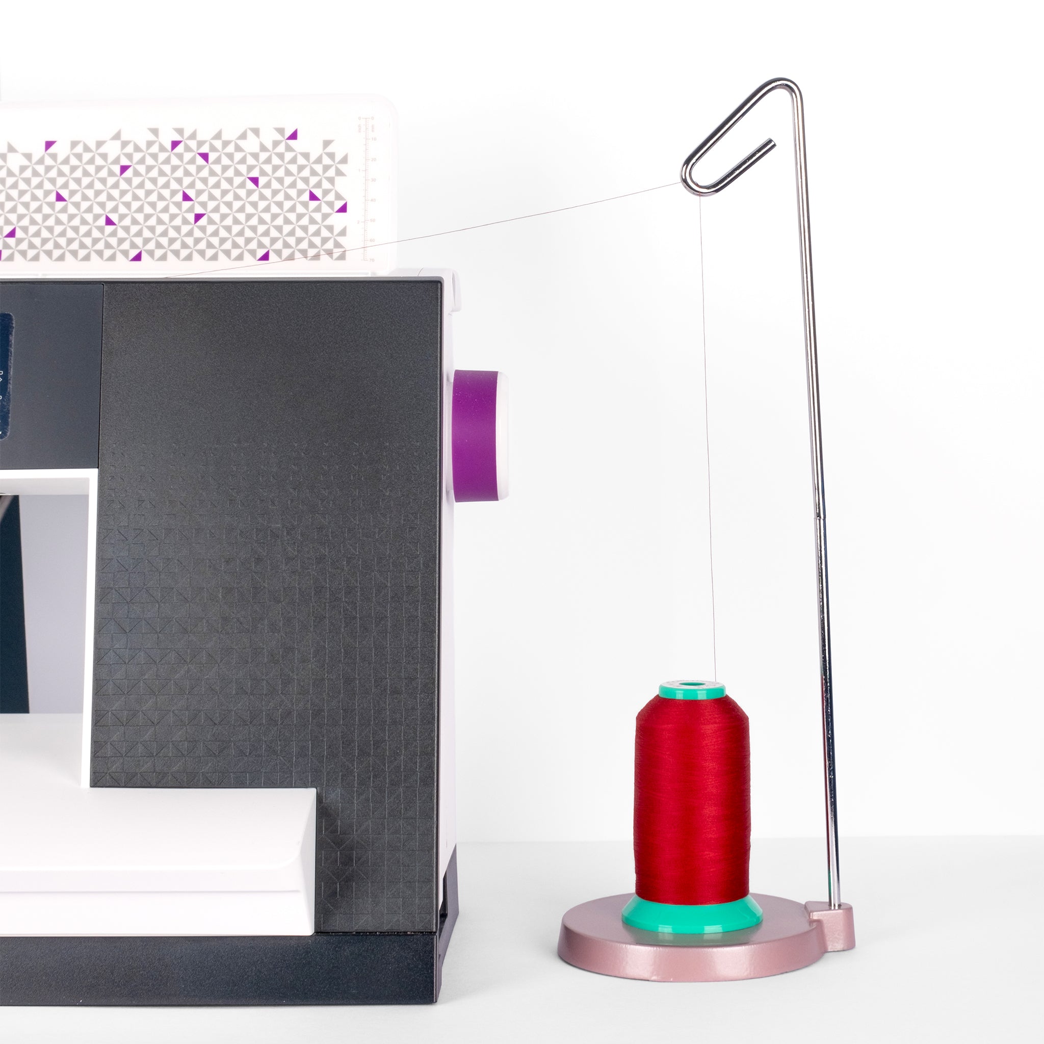 Red cone of perfection polyester thread on a stand with a white background