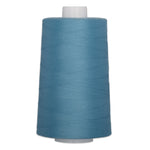 Large cone of blue polyester quilting thread on white plastic spool for sewing and quilting projects.