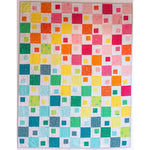 Colorful modern quilt with square blocks in rainbow gradient from warm reds and oranges at top transitioning to cool blues and greens at bottom.