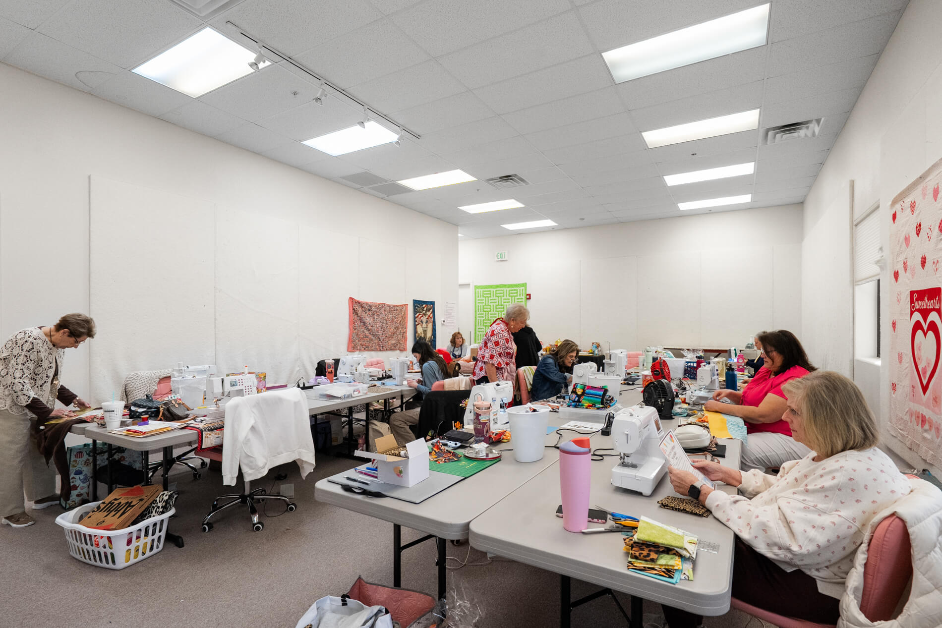 Room with tables and chairs where people are working on various projects.