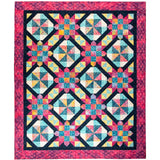 Colorful batik quilt featuring geometric star patterns in pink, teal, and yellow fabrics with a decorative pink border.