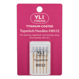 Packaging of YLI Threads titanium-coated topstitch needles, size #80/12, displayed on a pink background with the product information printed on it.
